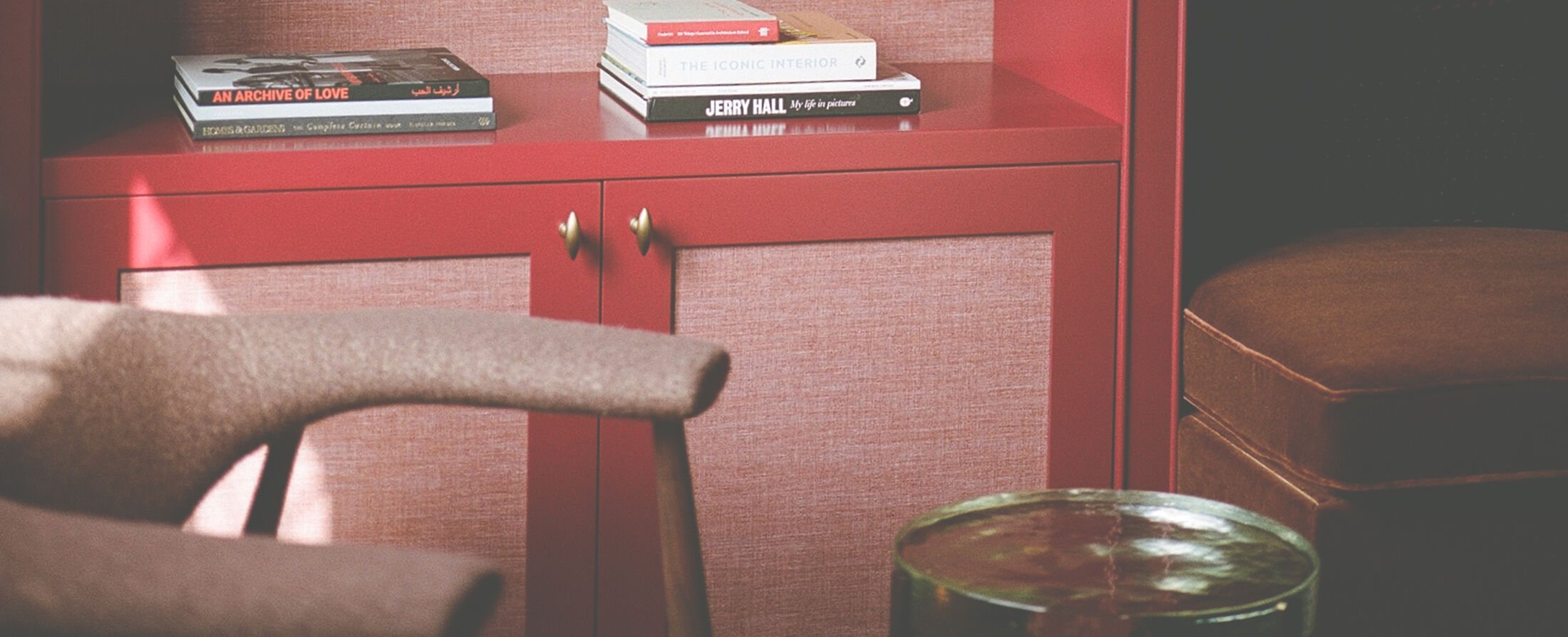Red lacquered study with linen-fronted cabinetry and books