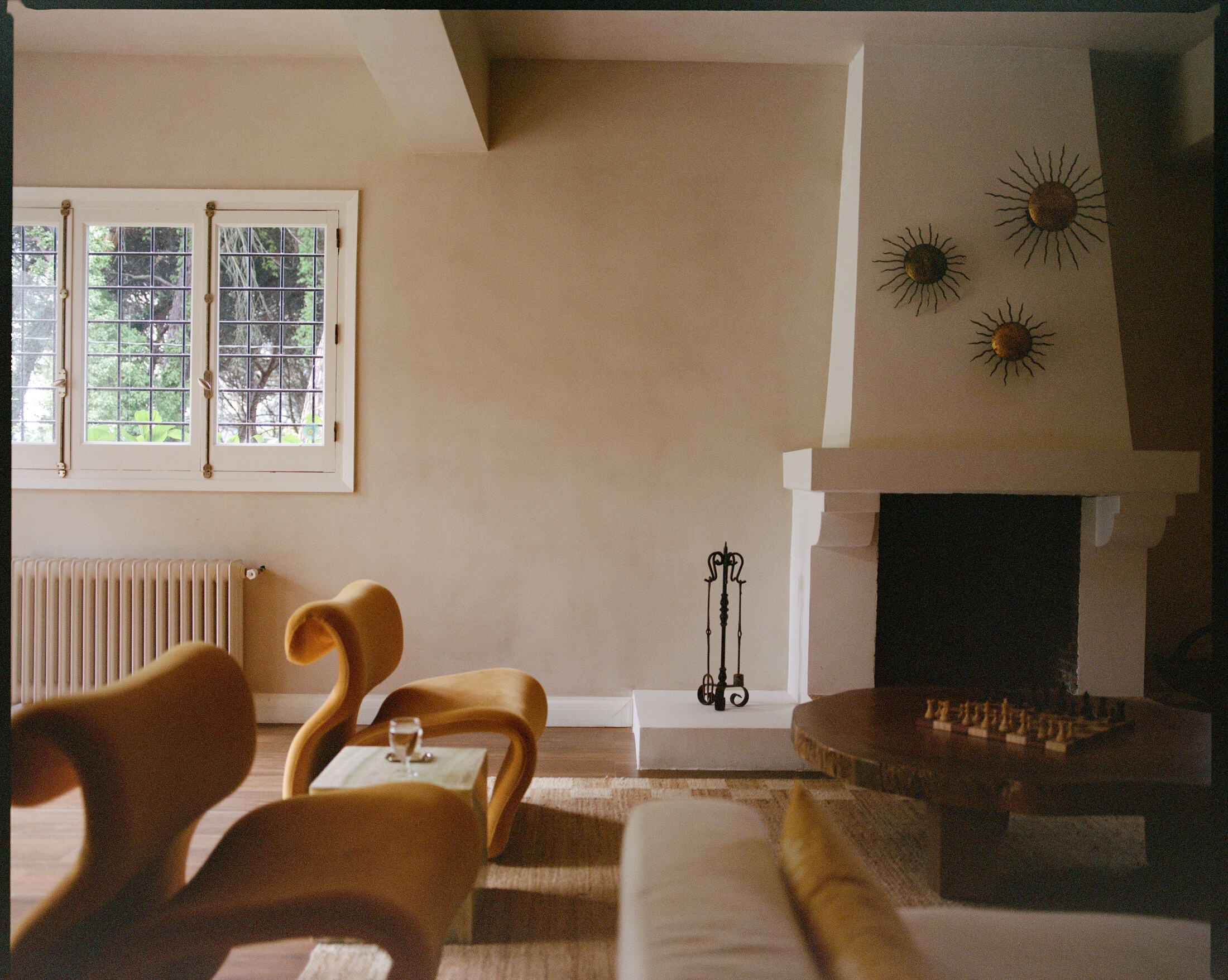 Living room with white plaster fireplace, gilded sun mirrors and carved chess table