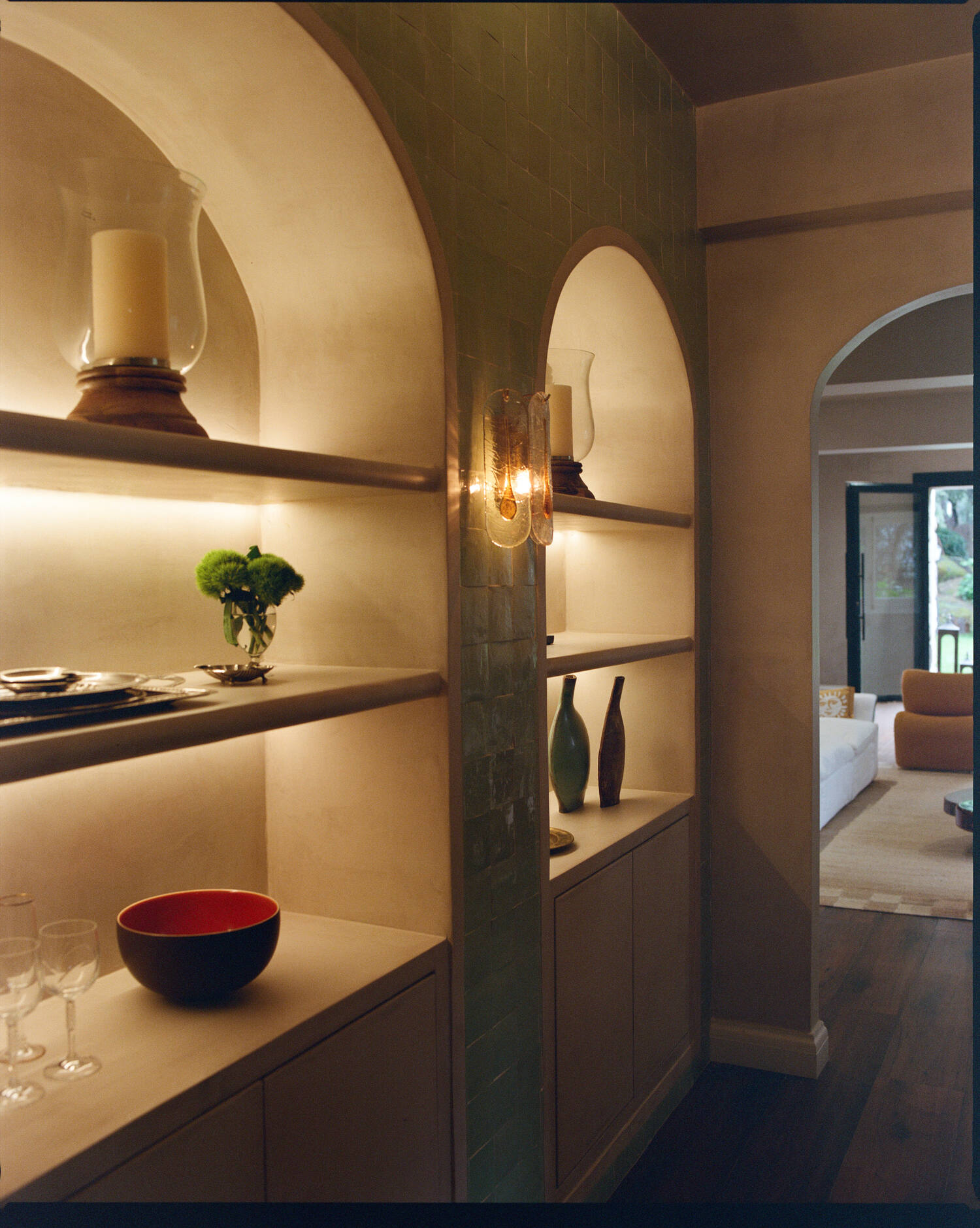 Arched plaster shelving niche with ceramics and lamplight