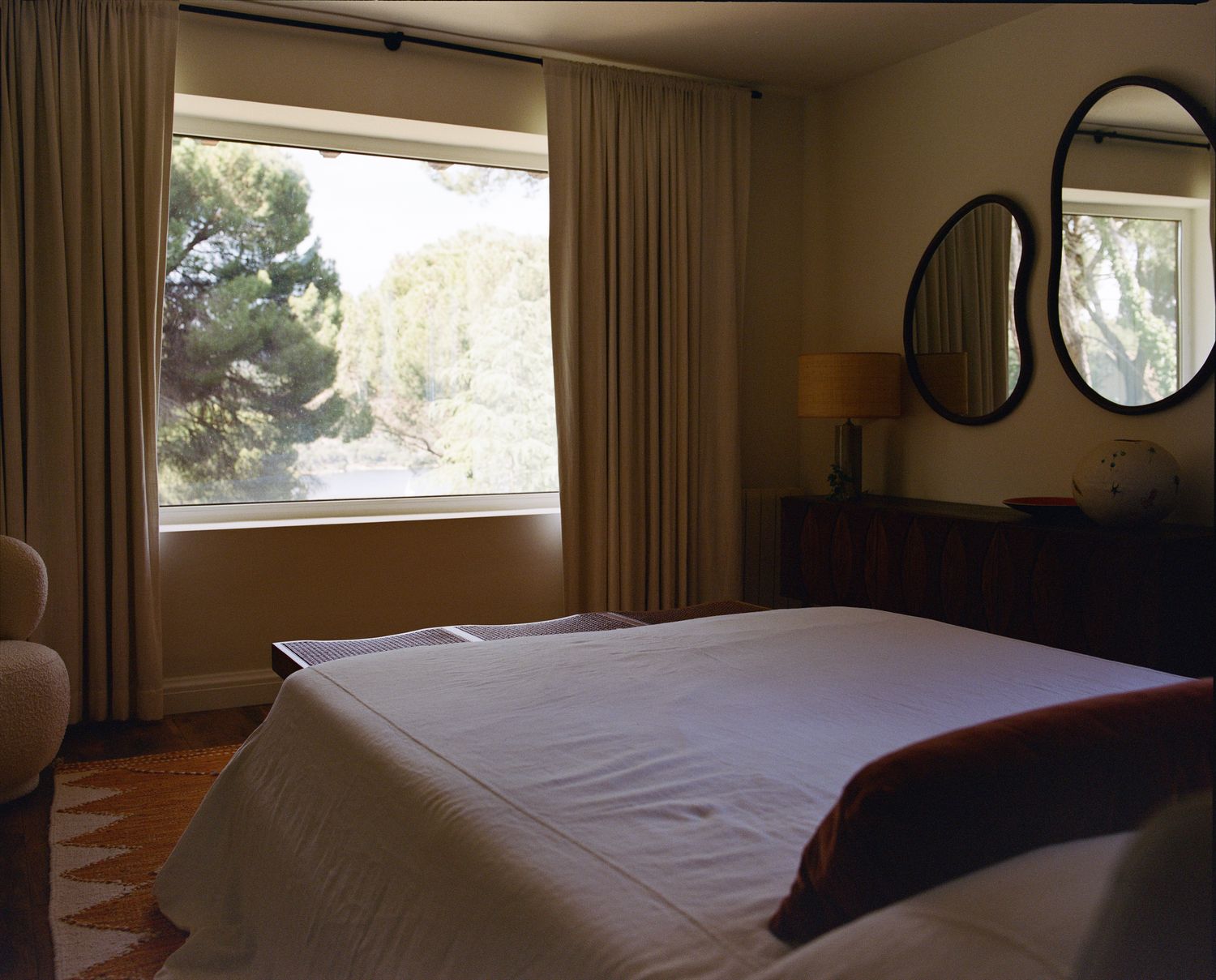 Bedroom with kidney-shaped mirrors and pine views