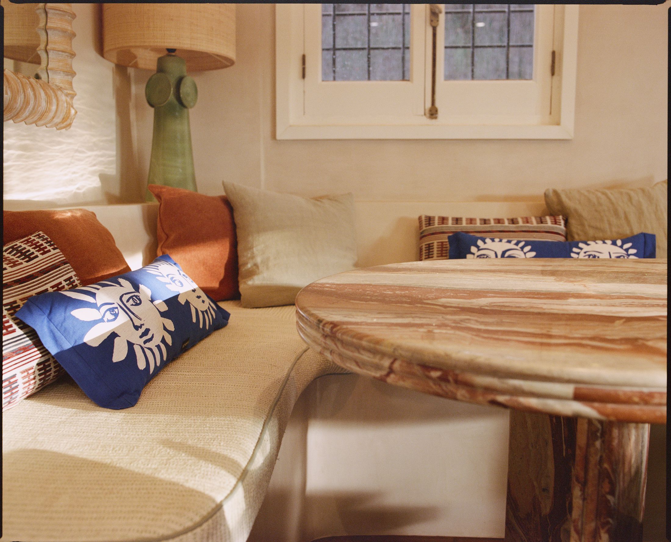 Cushioned window seat with patterned bolsters and a marble table