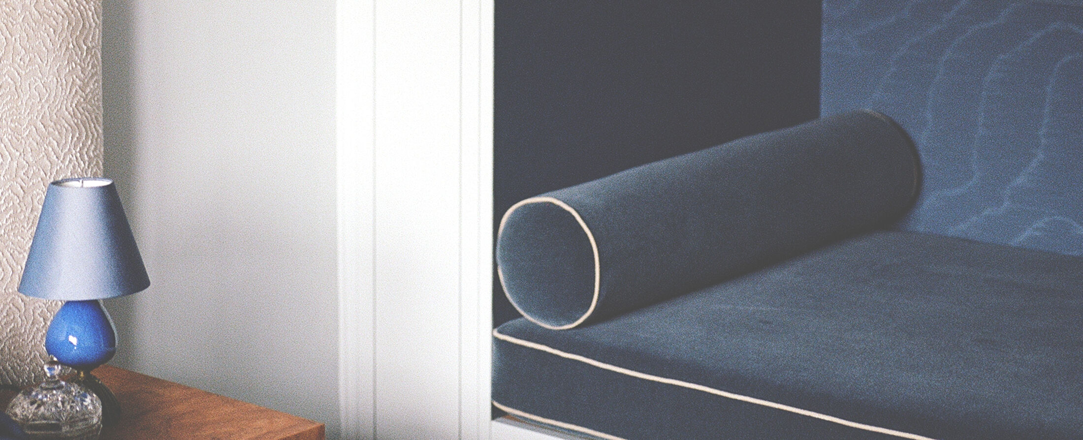 Bedroom with bouclé headboard, navy bedding and ceramic lamp