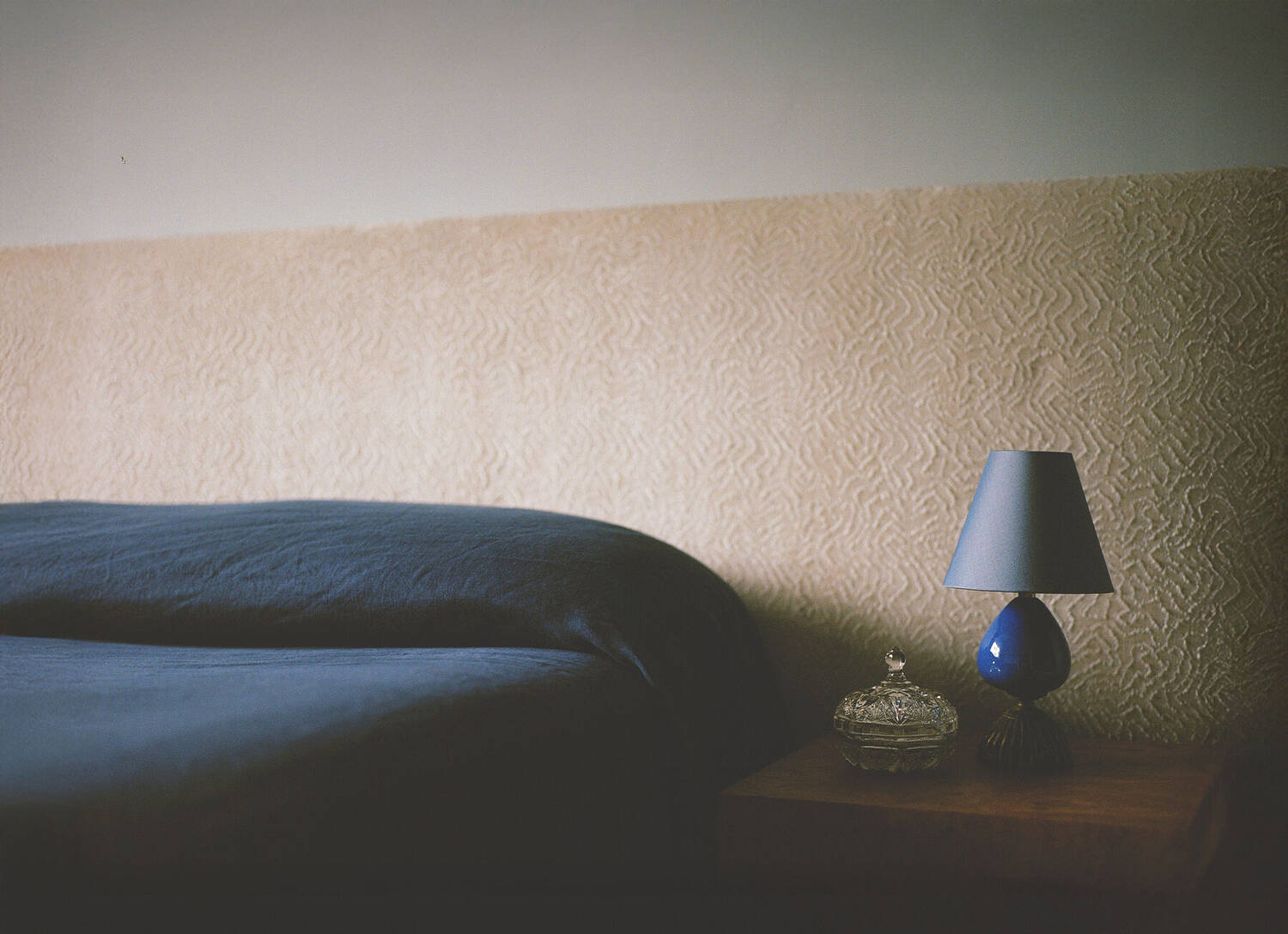 Bedroom corner with blue ceramic lamp on oak side table
